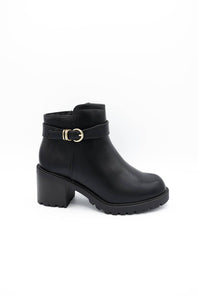 A pair of black leather ankle boots with chunky block heels, featuring a decorative strap with gold-tone buckles on the outer side and a side zipper, shown against a plain white background.
