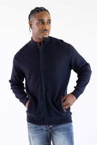Man wearing a navy mock neck jacket standing against a white background