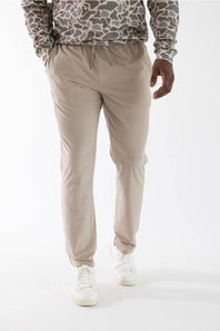 A person wearing beige drawstring jogger-style pants, a gray and brown camouflage hoodie, and white sneakers, photographed against a clean white studio background.