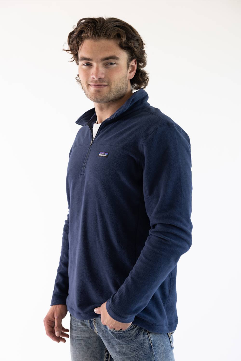 A man wearing a navy blue microfleece quarter zip pullover with a Patagonia logo on the upper left chest.