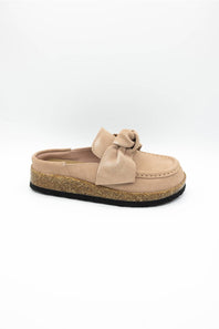 A single slip-on mule shoe in blush suede with a matching fabric bow on the vamp and a cork-textured midsole, shown against a plain white background.