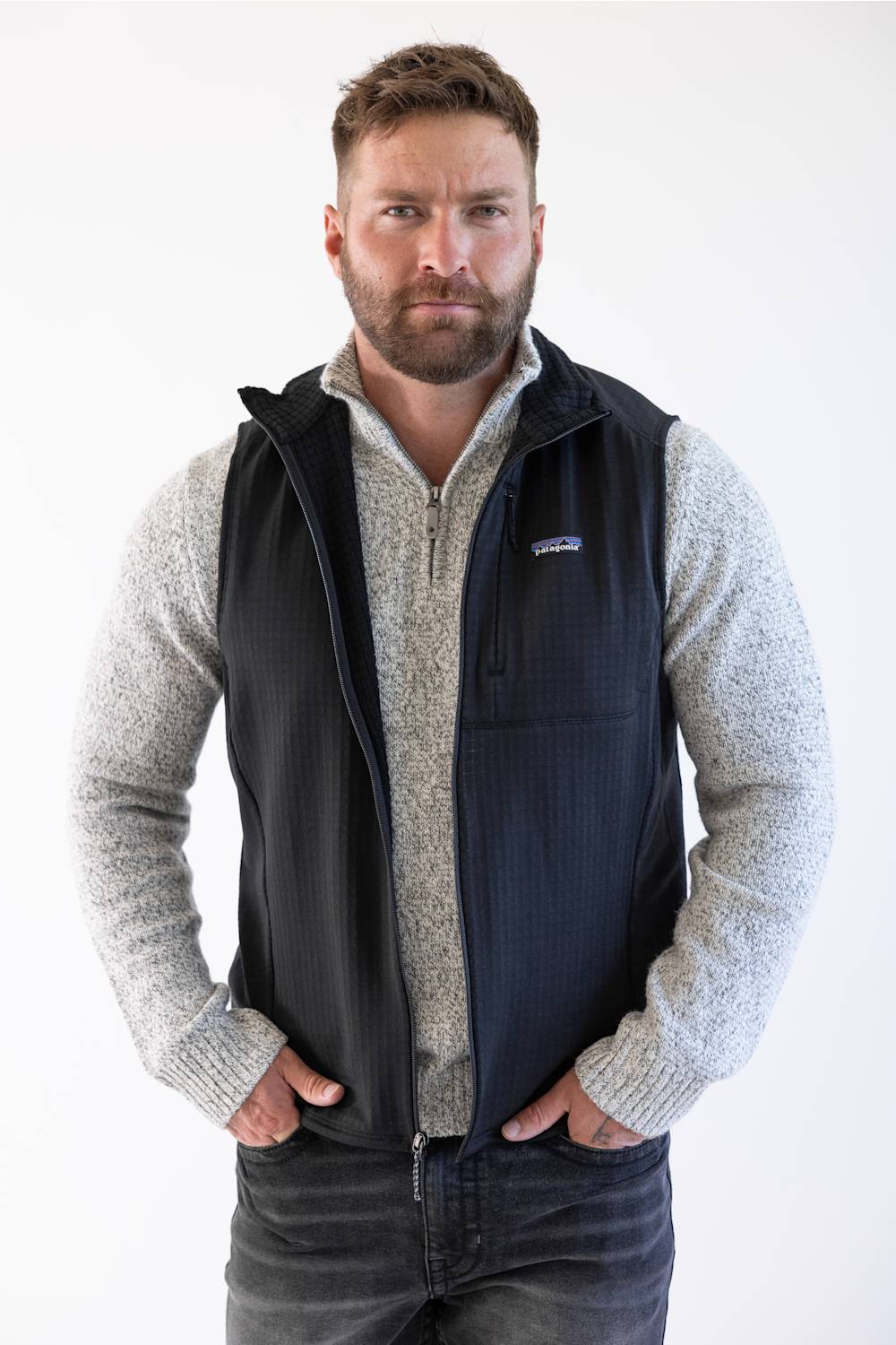 Front view of Patagonia Men's R1 Vest in Black styled over a grey quarter-zip sweater and dark jeans