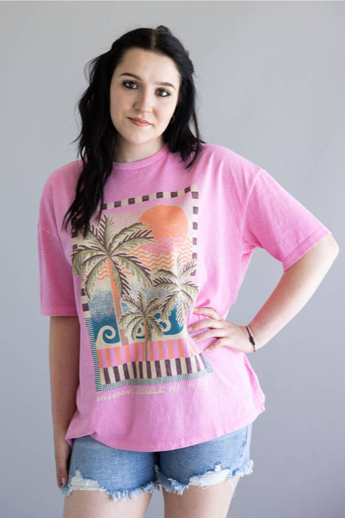 Woman wearing a pink t-shirt with a palm tree design on a plain background