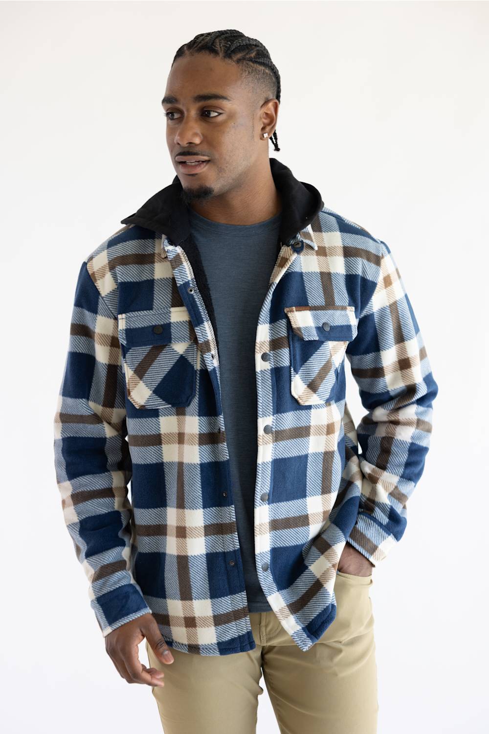 A man wearing a blue, brown, and beige plaid hooded flannel shirt over a dark gray t-shirt and khaki pants, photographed against a plain white studio background.