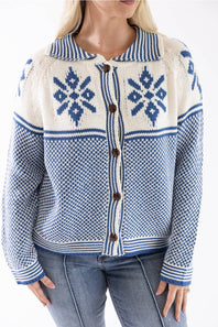 A woman wearing a blue and cream knit cardigan sweater with brown buttons, paired with blue jeans, against a plain white background.