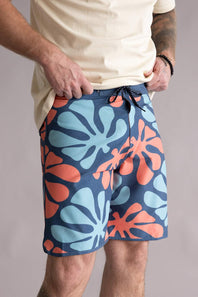 Person wearing colorful floral-patterned shorts on a plain background, showing the drawstring waistband. The shorts are named the Quiksilver Sol Tiles 19" Boardshorts for Men in Dark Denim.