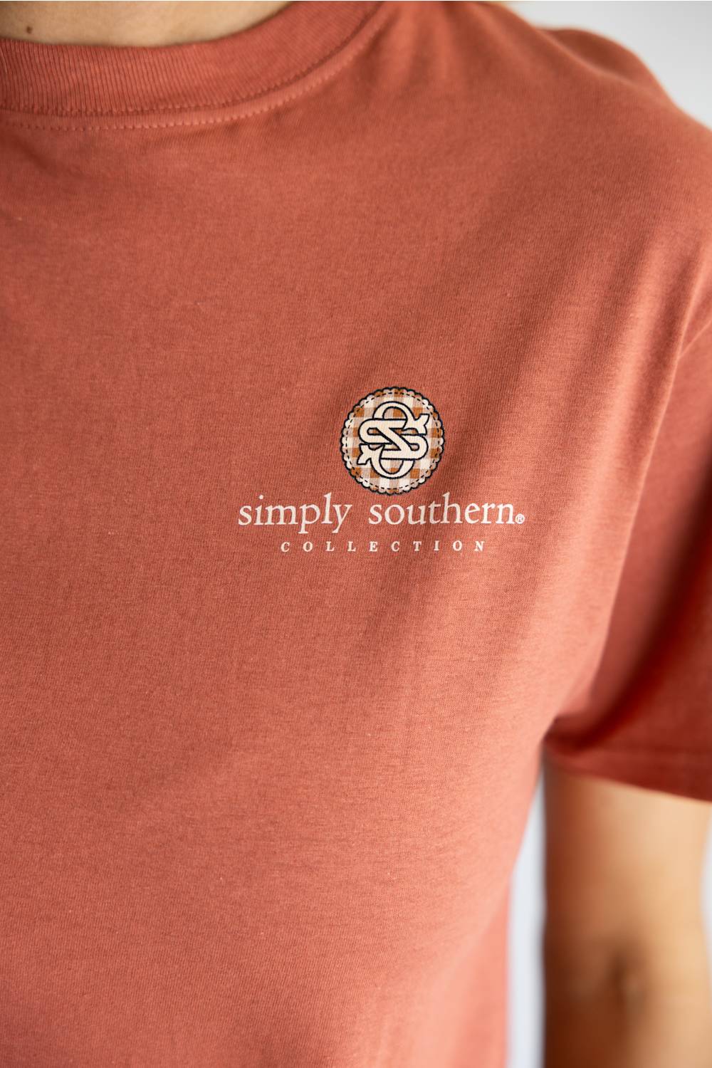 A terracotta-colored short-sleeve t-shirt shown from the back, featuring a graphic print of multiple flying mallards with handwritten-style text above and below. The brand 'simply southern.