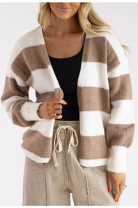 Close-up of a open-front striped knit cardigan with ribbed white cuffs, styled over a black top and drawstring pants.
