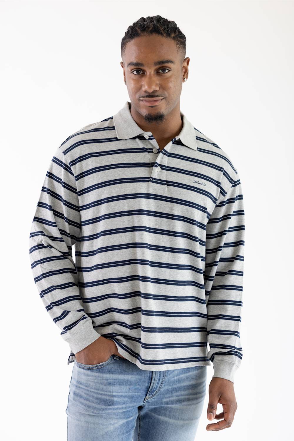 A man wearing a long-sleeve polo shirt with navy blue and white horizontal stripes, paired with light blue jeans, photographed against a plain white studio background.
