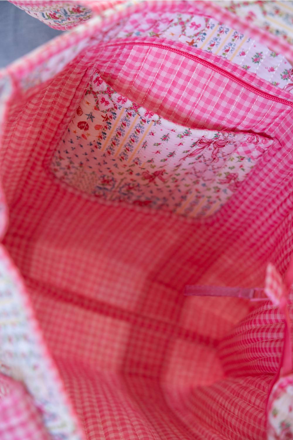 Close-up view of a pink and red gingham fabric bag interior with a floral patterned pocket lining.