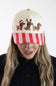 Model wearing the Simply Southern Santa Dogs Holiday Hat for Women in Cream and Red/Pink Stripe, featuring three embroidered dachshunds in holiday attire on the cream front panel and a red and pink striped visor.
