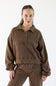 A woman modeling a brown cropped long-sleeve polo sweatshirt with matching brown pants against a plain white studio background.