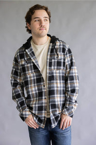 Model wearing the Split Men's long-sleeve hooded flannel shirt in a cream, black, and tan plaid pattern, featuring two chest flap pockets and an attached black hood with drawstrings against a gray studio background.