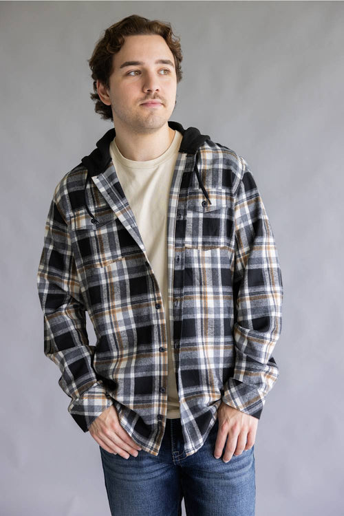 Model wearing the Split Men's long-sleeve hooded flannel shirt in a cream, black, and tan plaid pattern, featuring two chest flap pockets and an attached black hood with drawstrings against a gray studio background.