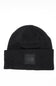 Front view of a black ribbed knit beanie featuring a folded cuff hem with a tonal square patch displaying The North Face logo against a white background.