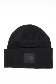 Front view of a black ribbed knit beanie featuring a folded cuff hem with a tonal square patch displaying The North Face logo against a white background.