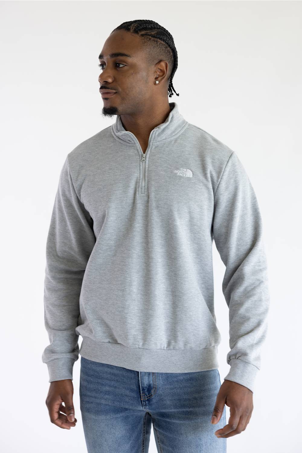 A man wearing a heather grey quarter zip The North Face men's sweatshirt with a white logo on the upper left chest.