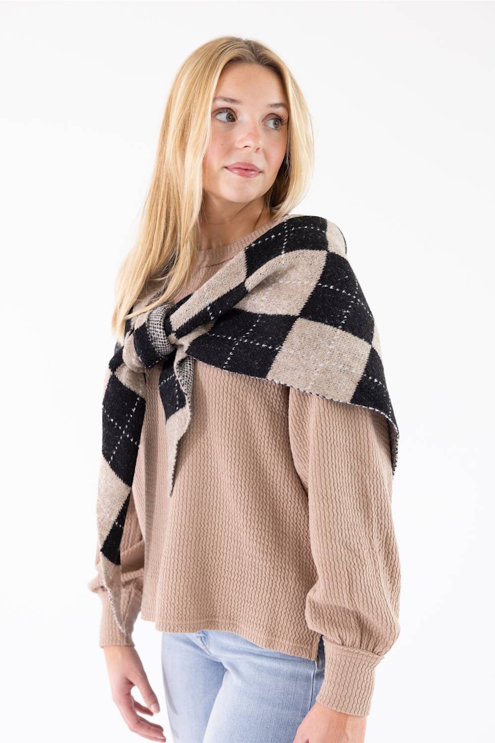 Front view of a woman wearing the Triangle Argyle Wool Scarf for Women in Taupe tied over her shoulders over a beige waffle-knit sweater.
