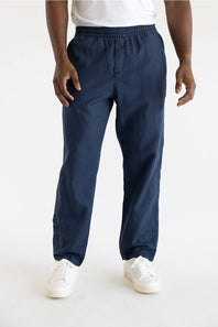 A person wearing navy blue jogger-style pants with an elastic waistband and cuffs, paired with a white top and white sneakers, shown against a plain light background.