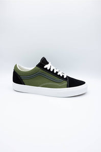 A low-top sneaker with an olive green and black color-blocked design, white laces, and a white rubber sole, photographed on a light gray studio background.
