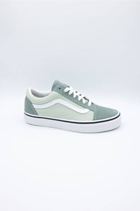 A single Vans Old Skool sneaker in a muted sage green colorway, featuring a white side stripe, white laces, and a white rubber sole, photographed against a seamless light gray studio background.