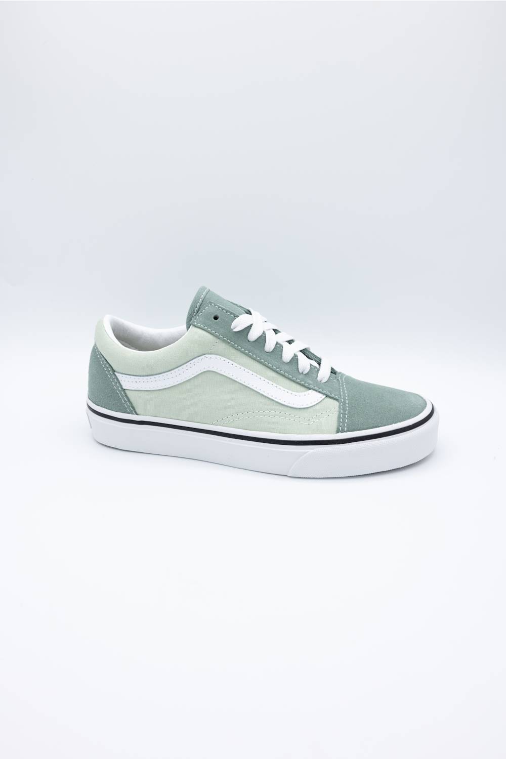 A single Vans Old Skool sneaker in a muted sage green colorway, featuring a white side stripe, white laces, and a white rubber sole, photographed against a seamless light gray studio background.