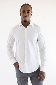 A man wearing a white long-sleeve button-down shirt and gray trousers, standing against a plain white studio background.