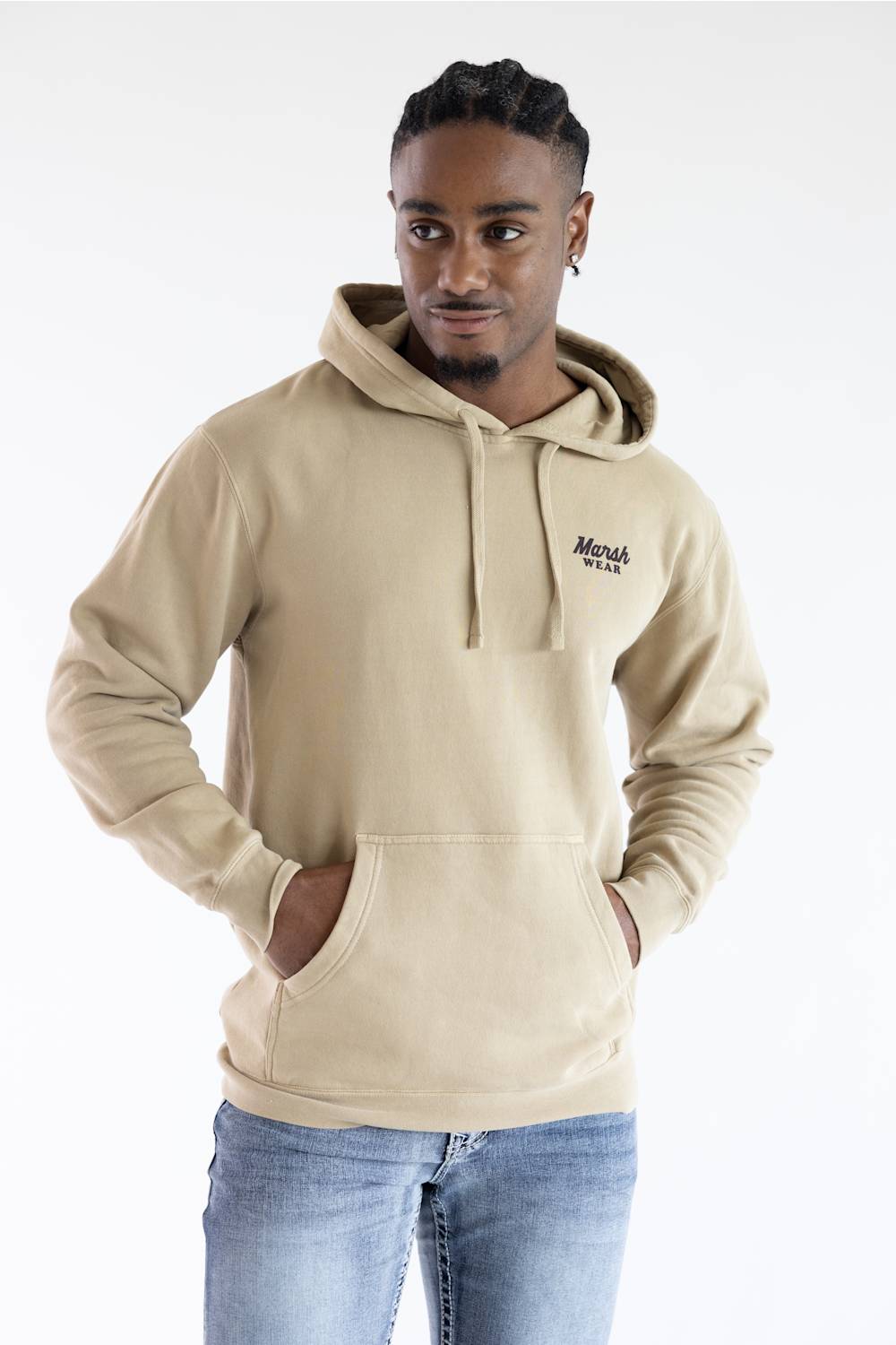 A man wearing a beige pullover hoodie with a drawstring hood and kangaroo pocket, featuring a small black embroidered 'Marsh' logo on the left chest, paired with blue jeans against a plain white background.