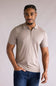 Man wearing a Denim & Flower Zip Sweater Polo for Men in Taupe shirt and blue jeans against a plain background
