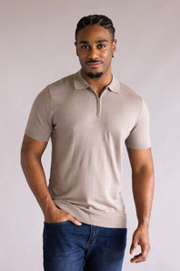Man wearing a Denim & Flower Zip Sweater Polo for Men in Taupe shirt and blue jeans against a plain background