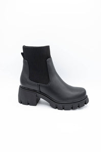 A single black ankle boot with a ribbed elastic side panel and a chunky lug sole, photographed on a clean white background.