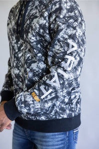 A person wearing a black and white camouflage-patterned hoodie with large white 'ARJAT' lettering down the sleeve, paired with blue jeans.