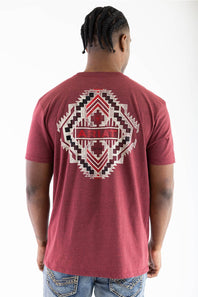 A man viewed from behind wearing a heathered red t-shirt with a large geometric patterned back graphic that features the brand name 'ARIAT' in red, and blue jeans, against a plain white background.