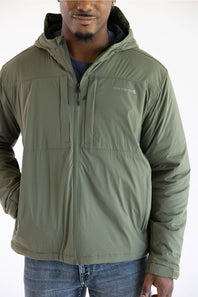 A male model posing against a solid white background in a dusty olive green hooded Carhartt zip-up jacket paired with blue jeans.
