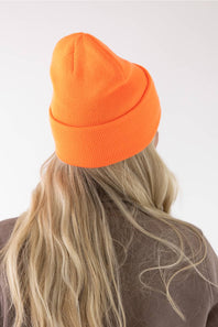 back view of a blonde woman modeling a orange Carhartt beanie 