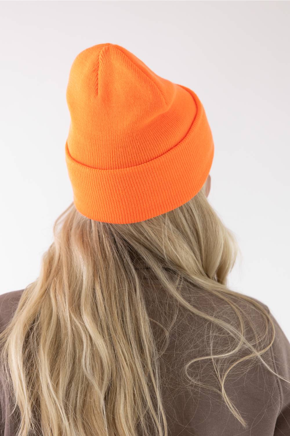 back view of a blonde woman modeling a orange Carhartt beanie 