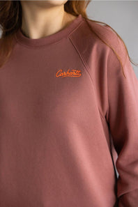 Dark red colored sweatshirt with orange Carhartt cursive letters on chest 