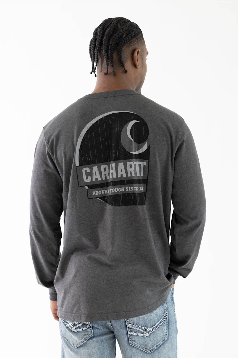 A man viewed from behind wearing a dark gray heather long-sleeve t-shirt with a large black and white Carhartt logo graphic on the back, paired with light blue jeans.