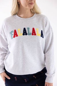 A blonde woman is shown in a cropped view, wearing an 1897 Active Falalala Patch Embroidered Fleece Sweatshirt for Women in Ice Grey featuring multi-colored 'Falalala' chenille patches, paired with dark blue patterned pants.