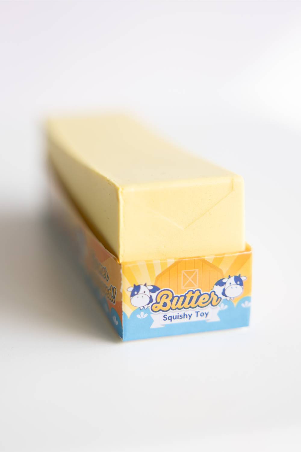 Butter-shaped squishy toy with packaging on a white background