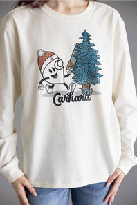A person wearing a cream-colored long-sleeve graphic t-shirt with a Carhartt logo and a cartoon character next to a pine tree, paired with blue jeans.