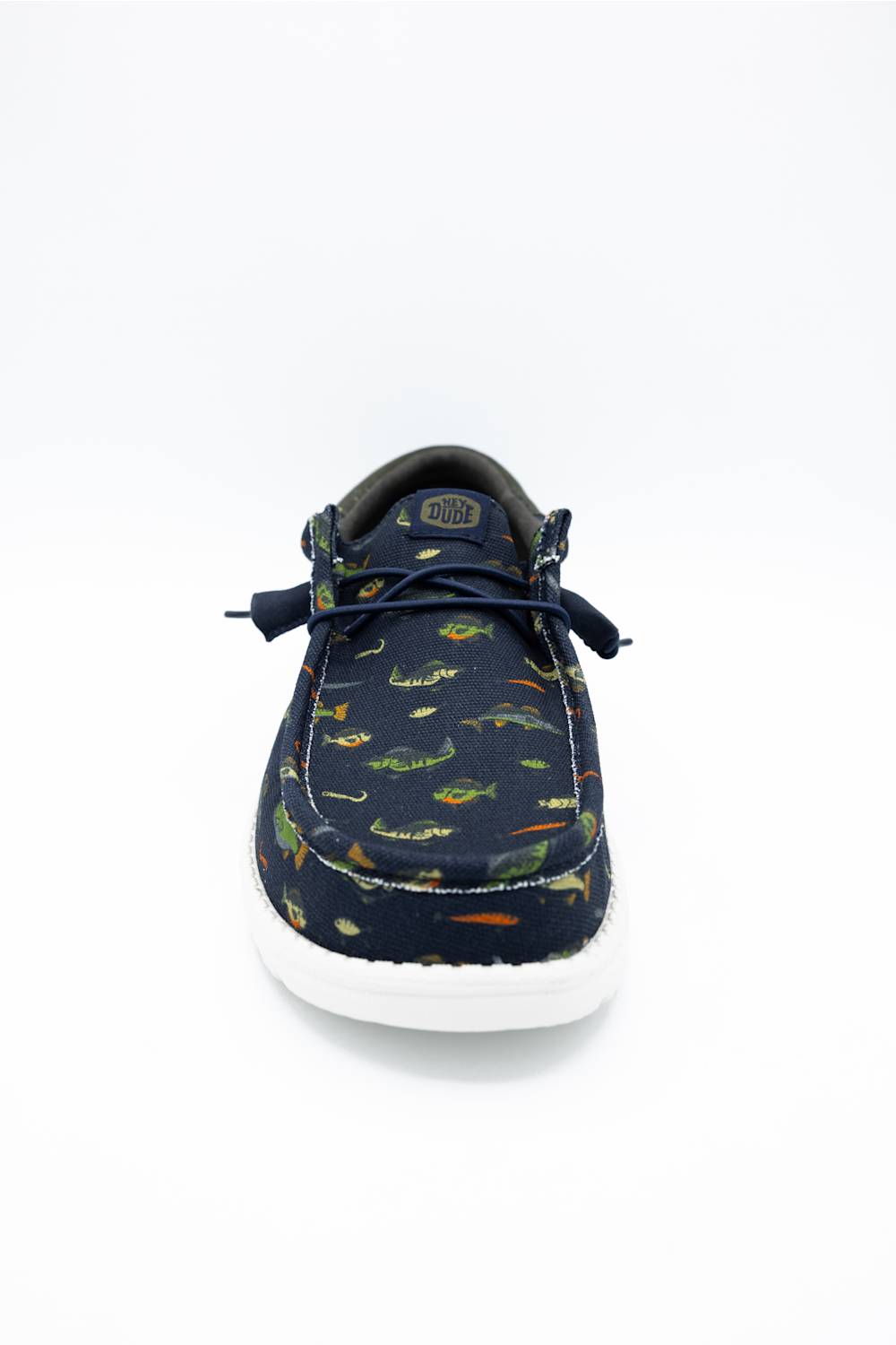 A pair of low-top casual shoes in navy blue canvas with a green, orange, and yellow fish pattern, featuring a white sole. One shoe is shown from the side displaying the pattern, while the other is positioned behind it showing the white outsole.