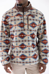 A man wearing a  quarter-zip fleece pullover with a Southwestern geometric pattern in cream, brown, blue, and red, paired with beige pants.