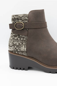 A brown suede ankle boot with a textured gray and white knit pattern panel on the side, a matching brown strap with a gold-tone buckle, and a chunky dark gray lug sole.