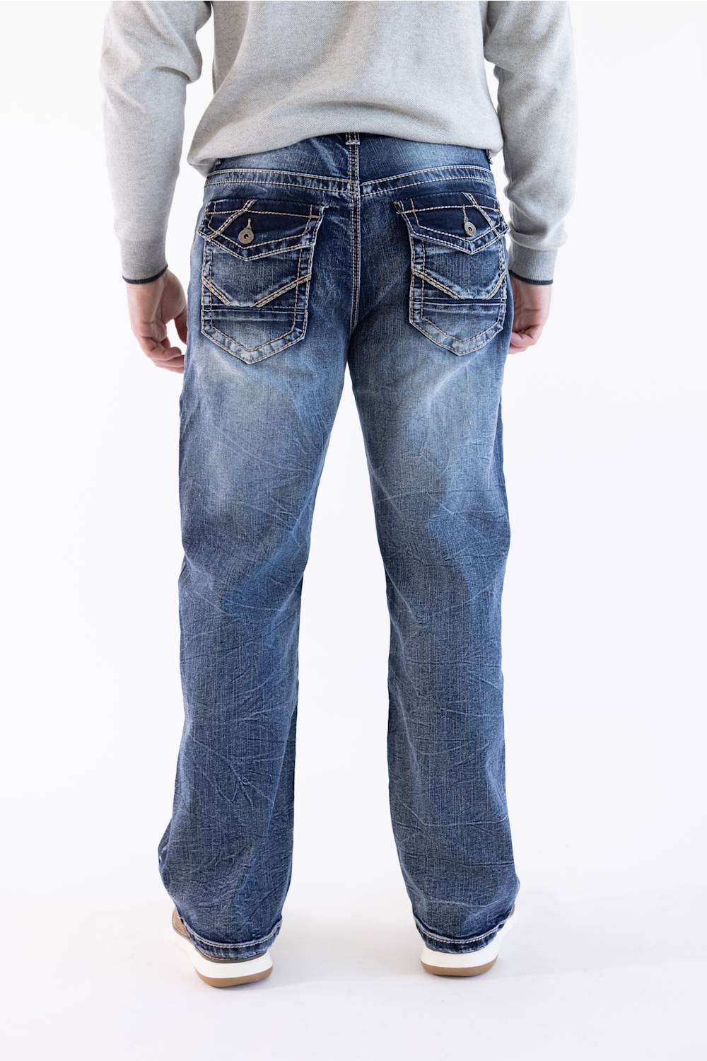 Men's medium-dark wash loose straight jeans viewed from the back, featuring button-flap utility pockets, tonal and contrast stitching, and a grey sweater.