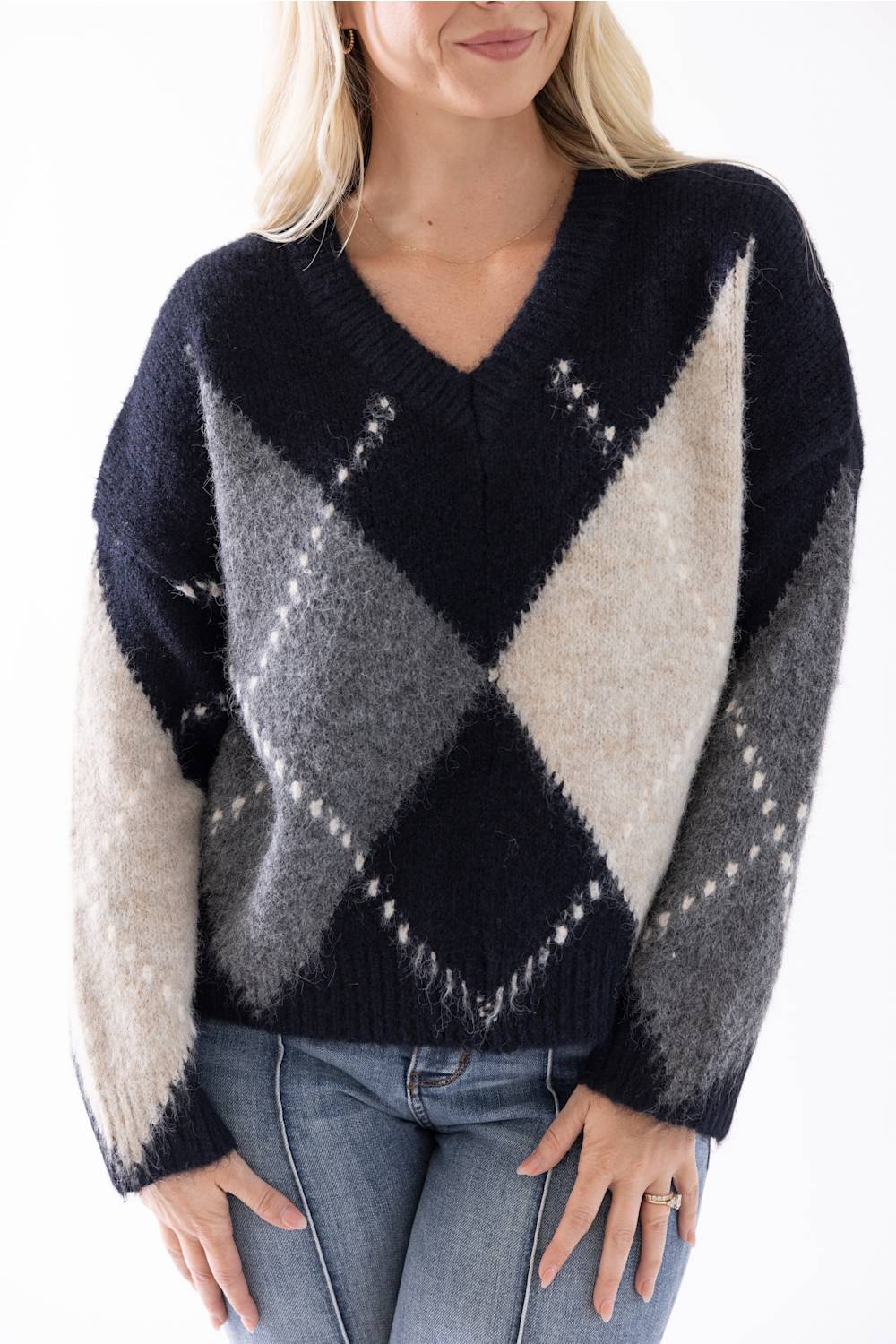up close shot of a woman modeling a argyle sweater and medium wash jeans