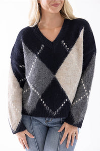 up close shot of a woman modeling a argyle sweater and medium wash jeans