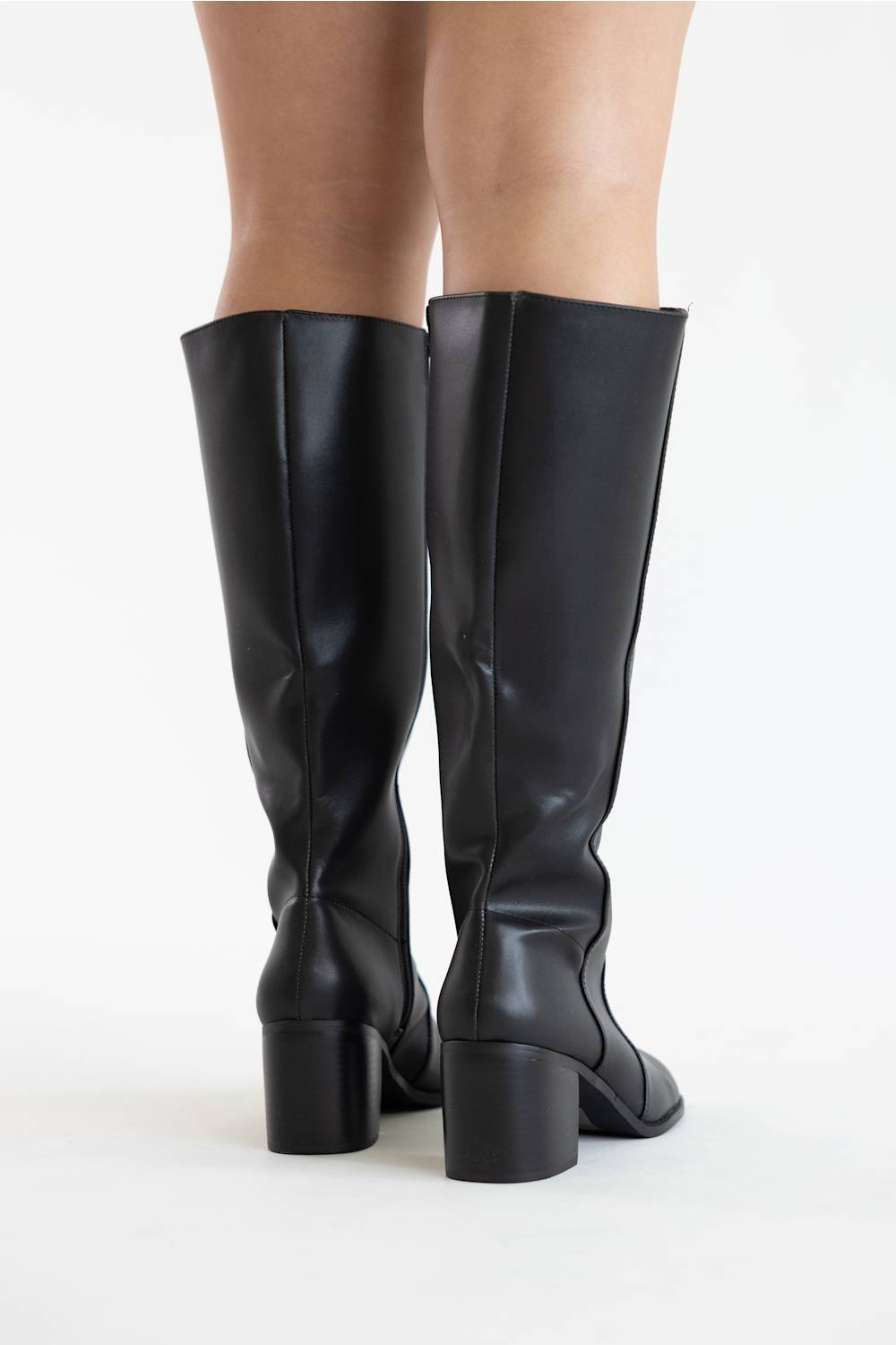 Black knee-high leather boots with block heels, shown from the back on a model against a white studio background.