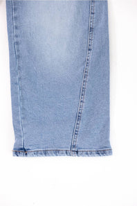 Close-up of the hem of light blue denim jeans showing the raw frayed edge and seam details against a white background.