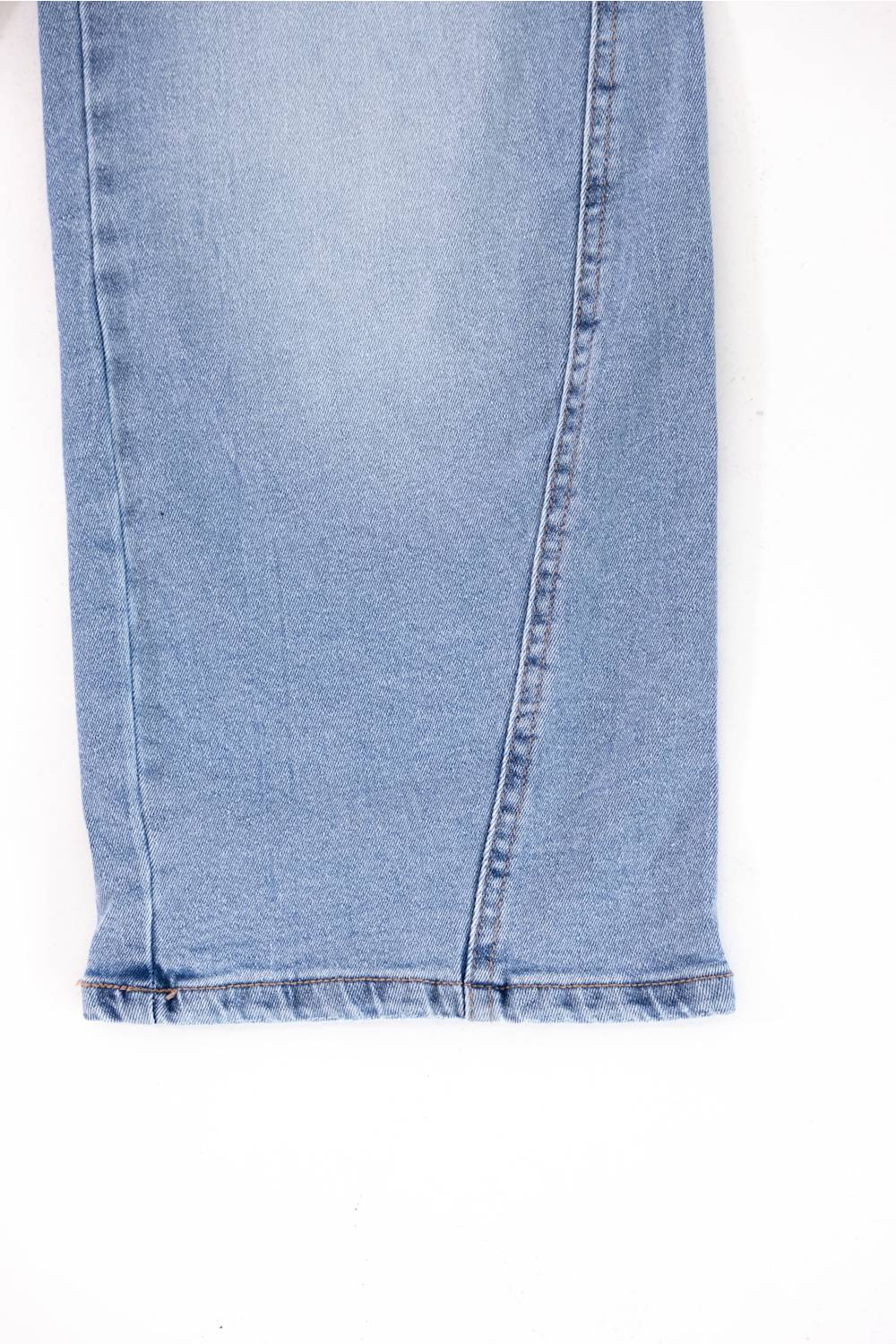 Close-up of the hem of light blue denim jeans showing the raw frayed edge and seam details against a white background.